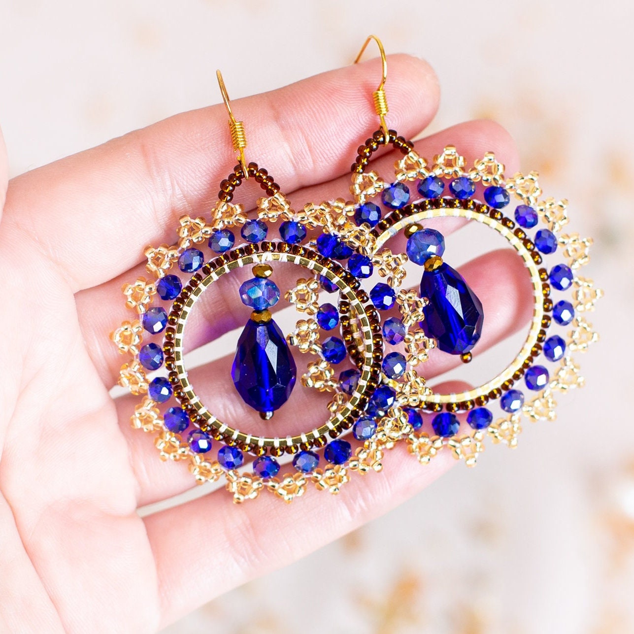 a pair of blue and gold earrings hanging from a branch